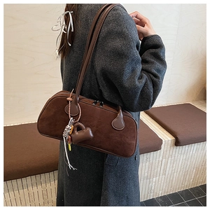 Close-up of a dark brown suede bowling shoulder bag with heart charms and tassels