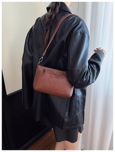 Detail of brown litchi pattern leather bag with silver zipper and embossed logo