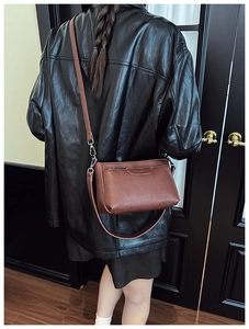 Close-up of a brown vintage crossbody bag with silver metal hooks on a model back view