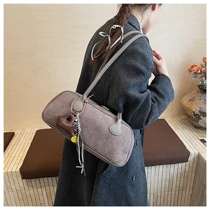 Mauve matte suede shoulder bag with brown pouch and smiley face charm shown on a model