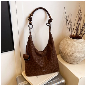 Détail du sac hobo à motif léopard avec des perles en bois sombres sur la bandoulière