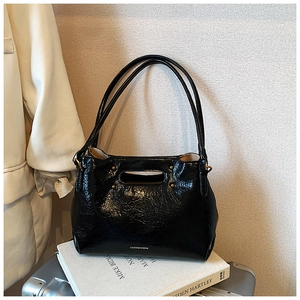 Detail of black glossy crinkle texture shoulder bag with gold studs and brand logo