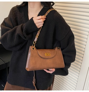 Détail du sac à chaîne en cuir marron foncé avec finition vintage et fermoir doré rotatif