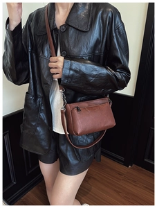 Detail of vintage brown crossbody bag with embossed lettering and adjustable strap
