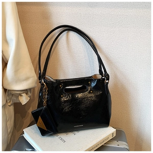Detail of black leather shoulder bag with glossy crinkle texture and mini side pouch