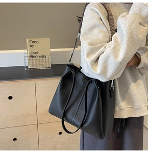 Detail of black pebbled leather tote bag showing large capacity and fine texture on a model