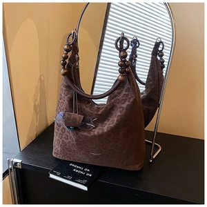 Detail of leopard print hobo bag with wood bead handles on a vintage cabinet