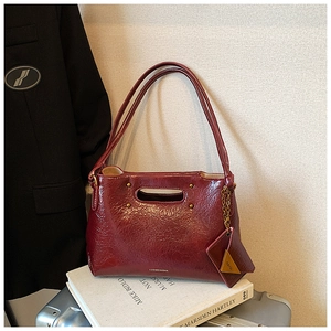 Detail of burgundy wax leather shoulder bag with metallic chain and handle design