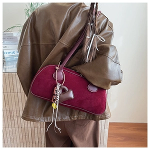 Close-up of burgundy suede shoulder bag with matte texture and decorative heart charms