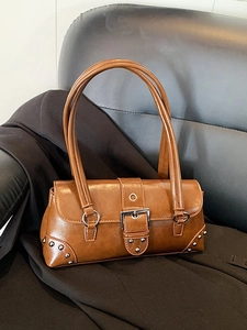 Sac sous le bras en cuir ciré marron avec boucle argentée et rivets sur canapé noir