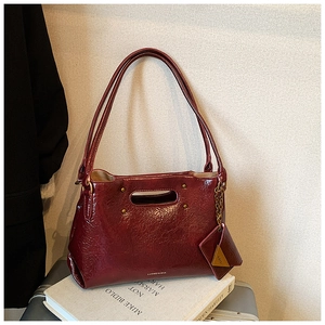 Detail of dark red patent leather handbag with cutout handle and small triangle coin pouch