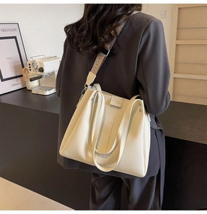 Detail of off-white leather tote bag featuring a decorative ethnic embroidered shoulder strap
