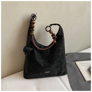 Detail of black suede tote bag with distinctive brown wooden bead handles and white logo