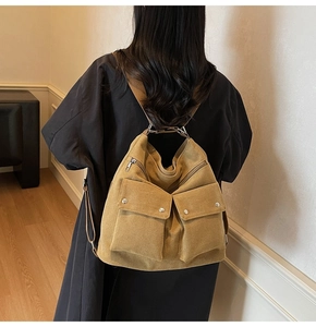 Rear view of model wearing a khaki canvas commuter backpack with two front utility pockets