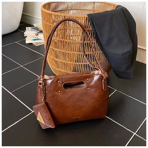 Detail of vintage brown leather handbag with unique oval cutout handle and mini coin purse