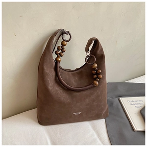 Détail du sac hobo en daim marron avec perles en bois et bandoulière en corde tressée