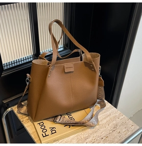 Detail of brown litchi pattern tote bag with jacquard strap and brand logo engraving