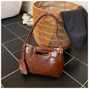 Close-up of vintage brown waxed leather tote bag with rivet detail and metal charm