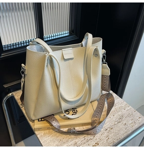 Detail of lychee pattern leather tote bag with geometric woven wide shoulder strap