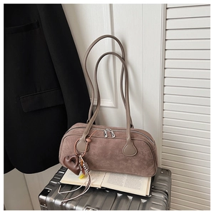 Detail of tan suede Boston bag with silver zippers, slim straps and heart charm on suitcase