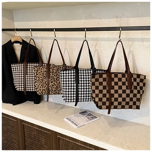 Detail view of large tote bags in houndstooth, leopard, and checkerboard woven fabrics