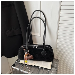 Detail of black matte bowling bag with dual zippers and decorative charms on a suitcase