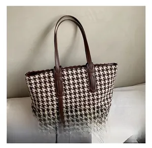 Detail of houndstooth tote bag featuring premium brown leather straps and texture
