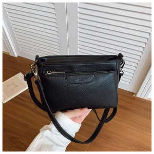 Detail of black lychee grain leather crossbody bag with metal zipper and embossed logo