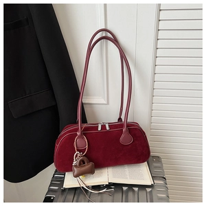 Detail view of burgundy suede bowling bag with twin zippers and small leather charm