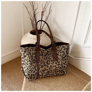 Detail shot of leopard print tote bag with brown leather handles in elegant home setting
