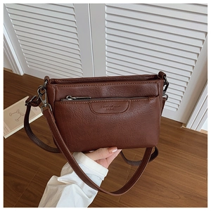Close-up of brown faux leather crossbody bag with lychee texture and front zip pocket