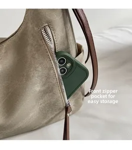 Close-up of khaki textured shoulder bag with front zipper pocket and brown leather strap