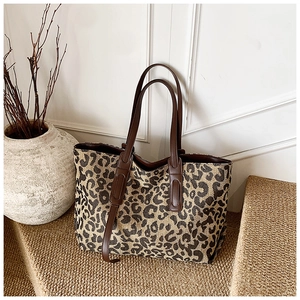 Detailed macro view of leopard print tote bag fabric and brown leather shoulder strap