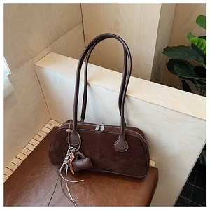 Detail view of coffee brown matte suede bag featuring decorative heart pendant and long tassels