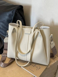 Chic beige pebbled leather tote bag with woven shoulder strap in a minimalist setting