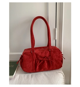Détail du sac Boston en daim rouge avec nœud élégant et poches latérales plissées