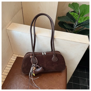 Detailed shot of a vintage dark brown suede bowling bag with heart charm and silver zips
