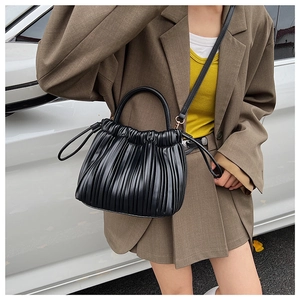 Close-up of black pleated bucket bag with gold hardware and elegant cloud-shaped texture
