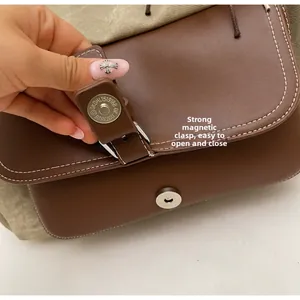 Detalle de hebilla magnética de metal en bolso de media luna vintage de cuero y lona