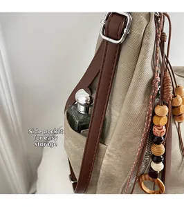 Detail of canvas tote side pocket and leather strap with wooden bead tassel decoration