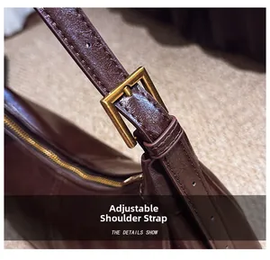 Close-up of adjustable shoulder strap and hardware on dark reddish-brown leather bag