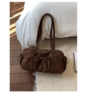 Détail du sac cylindre en daim marron avec nœud élégant et design plissé vintage