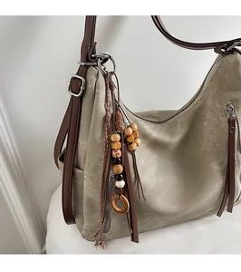 Detail of khaki canvas tote bag with brown leather strap and wooden bead tassel ornament