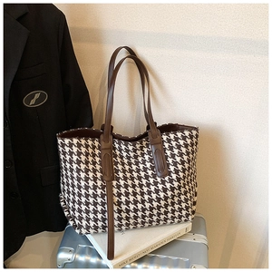 Detail of houndstooth tote bag on luggage with leather handles and large capacity space