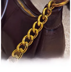 Macro shot of high-shine gold chain strap and dark brown polished leather on the handbag