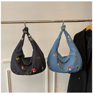 Détail de motifs brodés de champignons et marguerites sur sacs hobo en denim