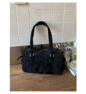Gros plan d'un sac bandoulière en velours noir avec nœud décoratif et poche plissée