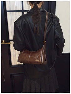 Close-up of glossy brown faux leather shoulder bag with gold brand logo lettering