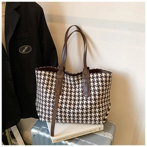 Detail of large houndstooth tote bag showing woven fabric texture and faux leather straps