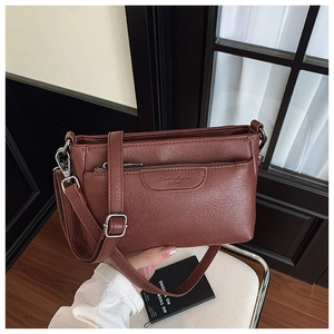 Detail of caramel leather crossbody bag featuring adjustable strap and silver metal buckle